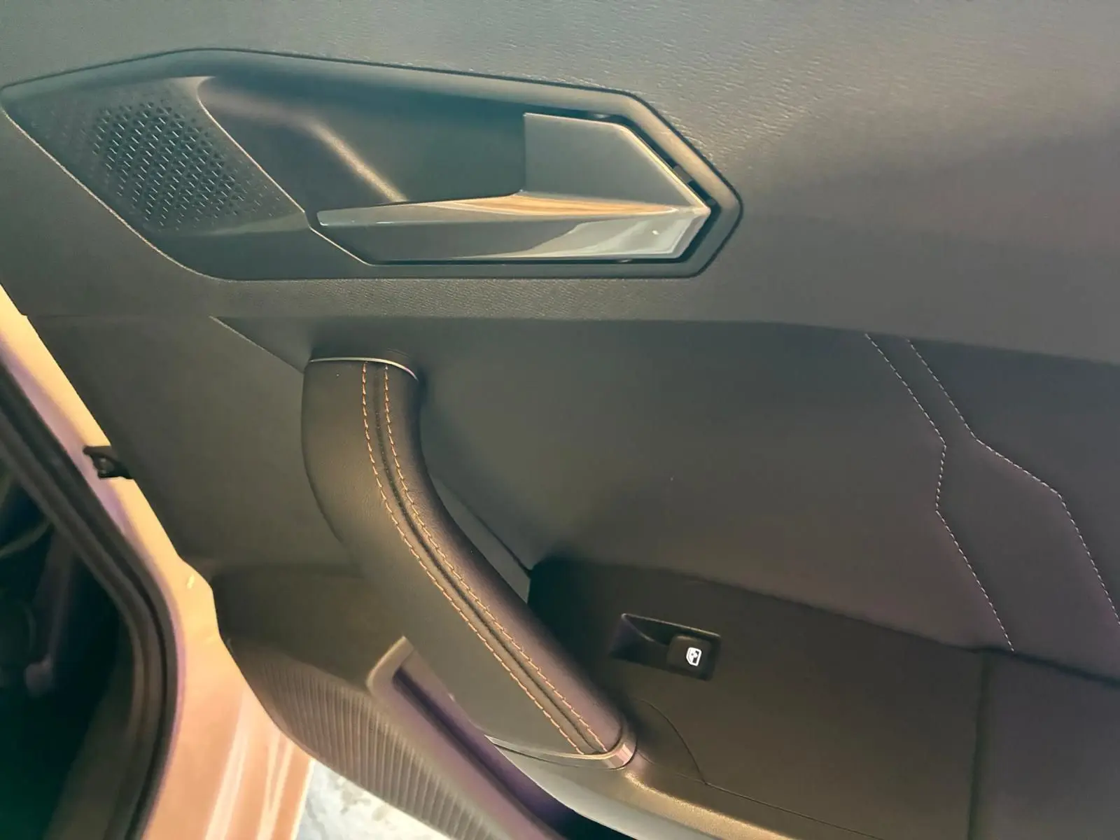 Détail de la poignée intérieure côté gauche d’une CUPRA LEON ST blanche, avec surpiqûres et bouton de lève-vitre.