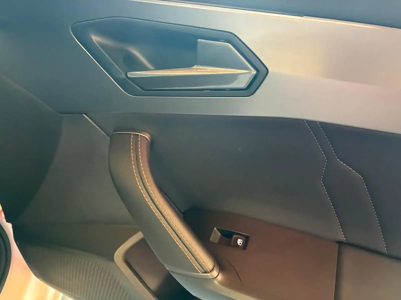 Gros plan sur la poignée de porte intérieure côté gauche en cuir noir avec surpiqûres contrastantes du CUPRA Leon ST 2024.