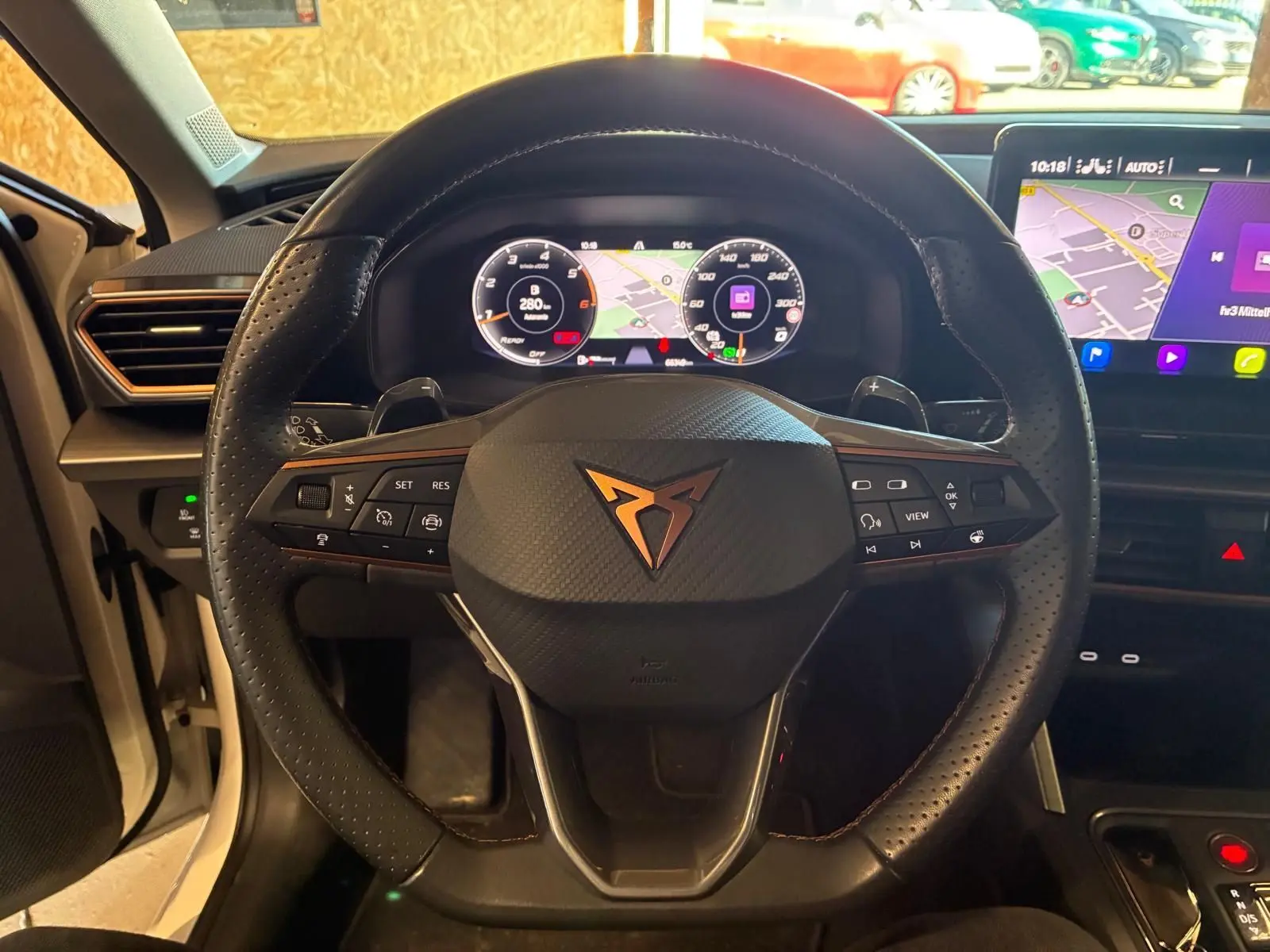 Vue intérieure centrée sur le volant noir perforé avec logo CUPRA et tableau de bord digital lumineux.