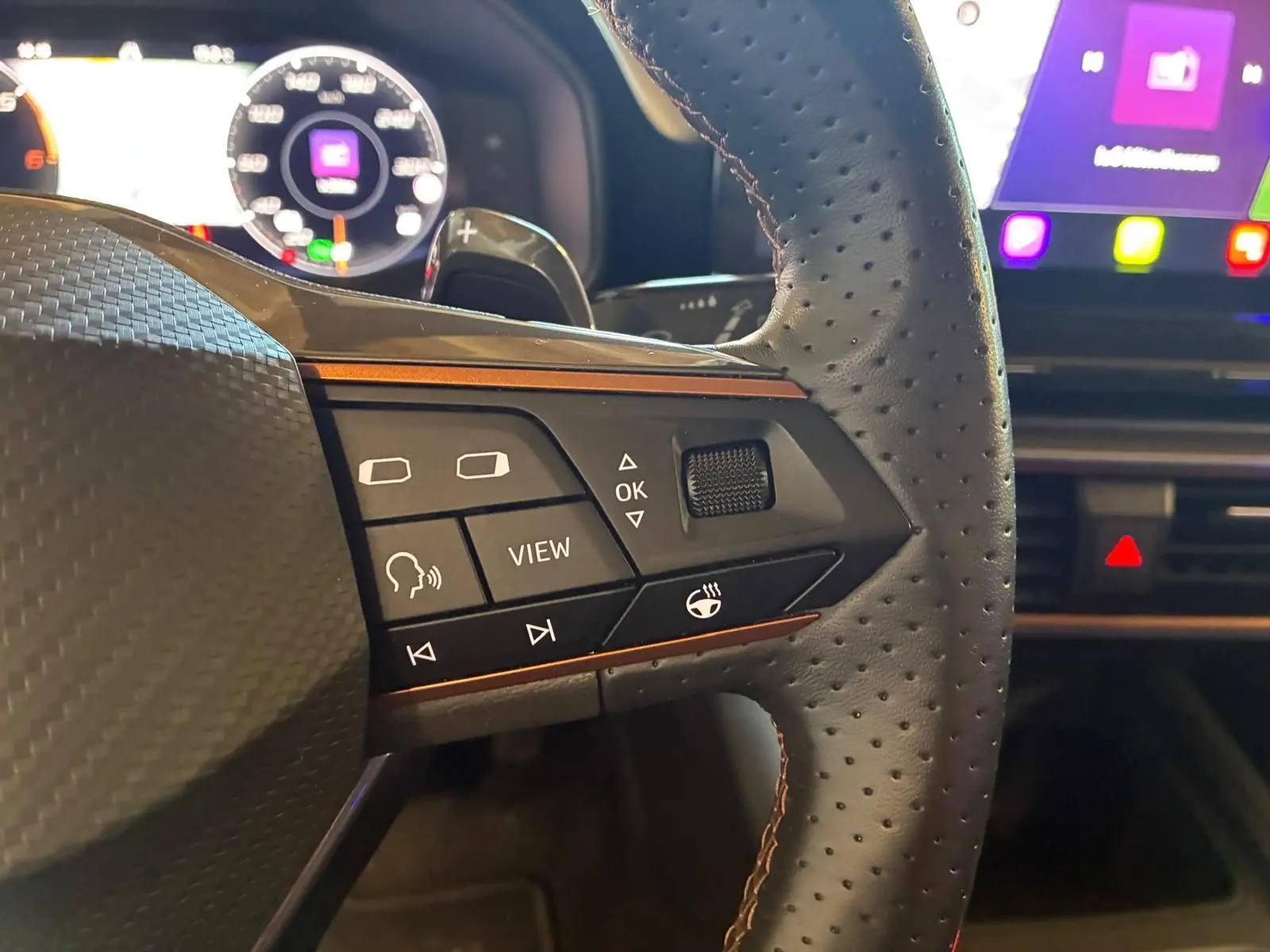 Gros plan sur le volant perforé noir de la CUPRA LEON ST 2024 avec commandes multifonctions et tableau de bord numérique.