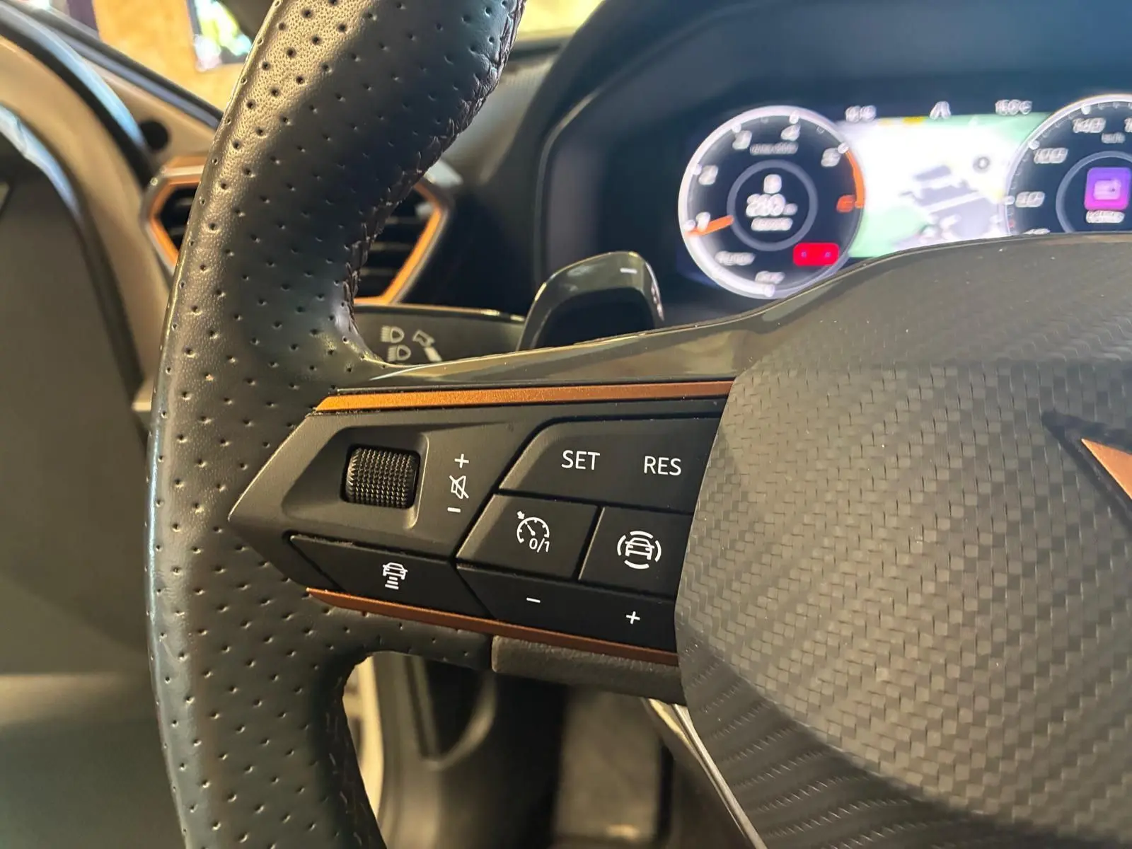 Gros plan sur le volant perforé noir de la CUPRA LEON ST 2024 avec commandes de régulateur et tableau de bord numérique.