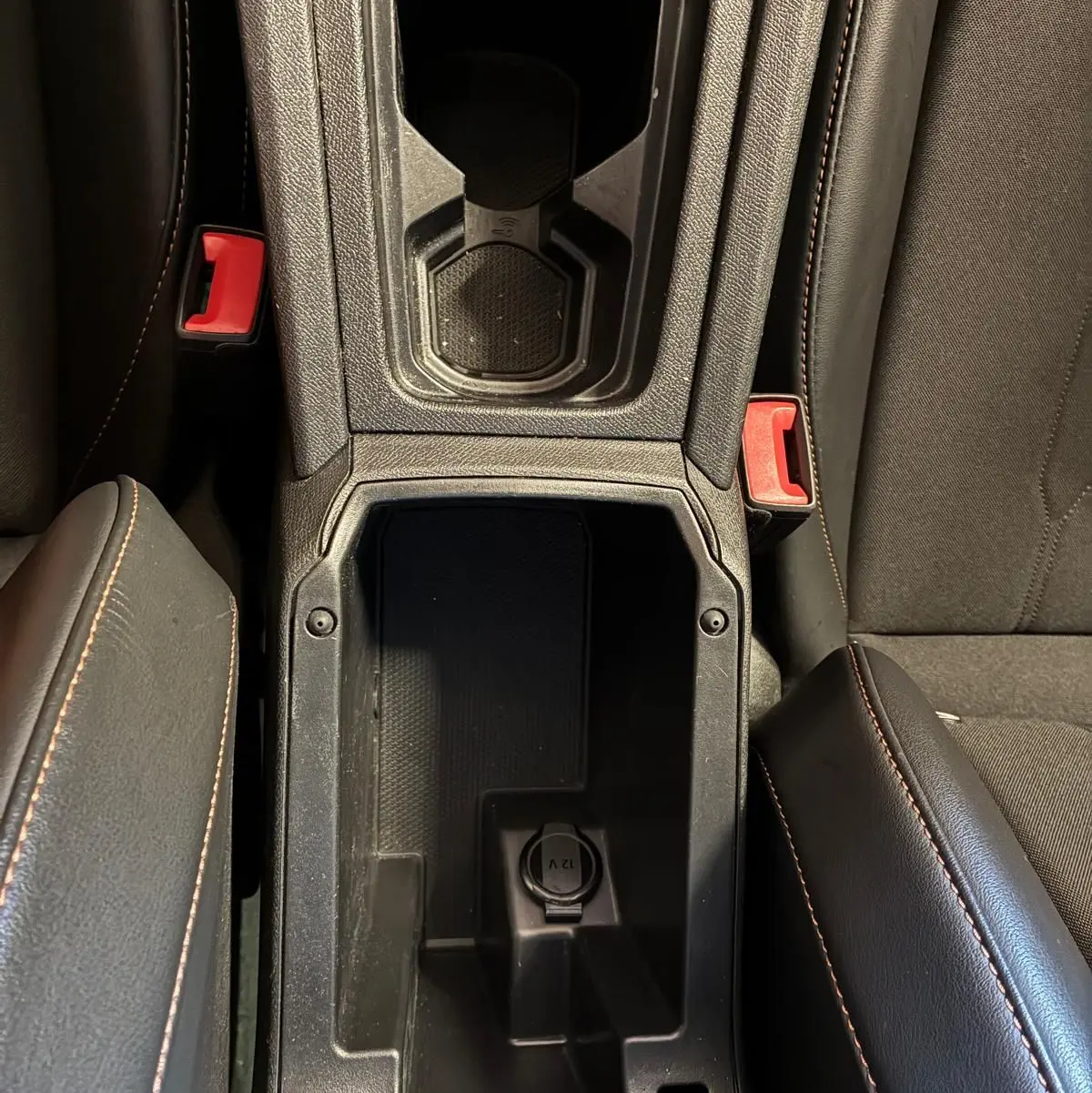 Vue plongeante sur la console centrale noire avec porte-gobelets et prise 12V du CUPRA LEON ST 2024 intérieur.