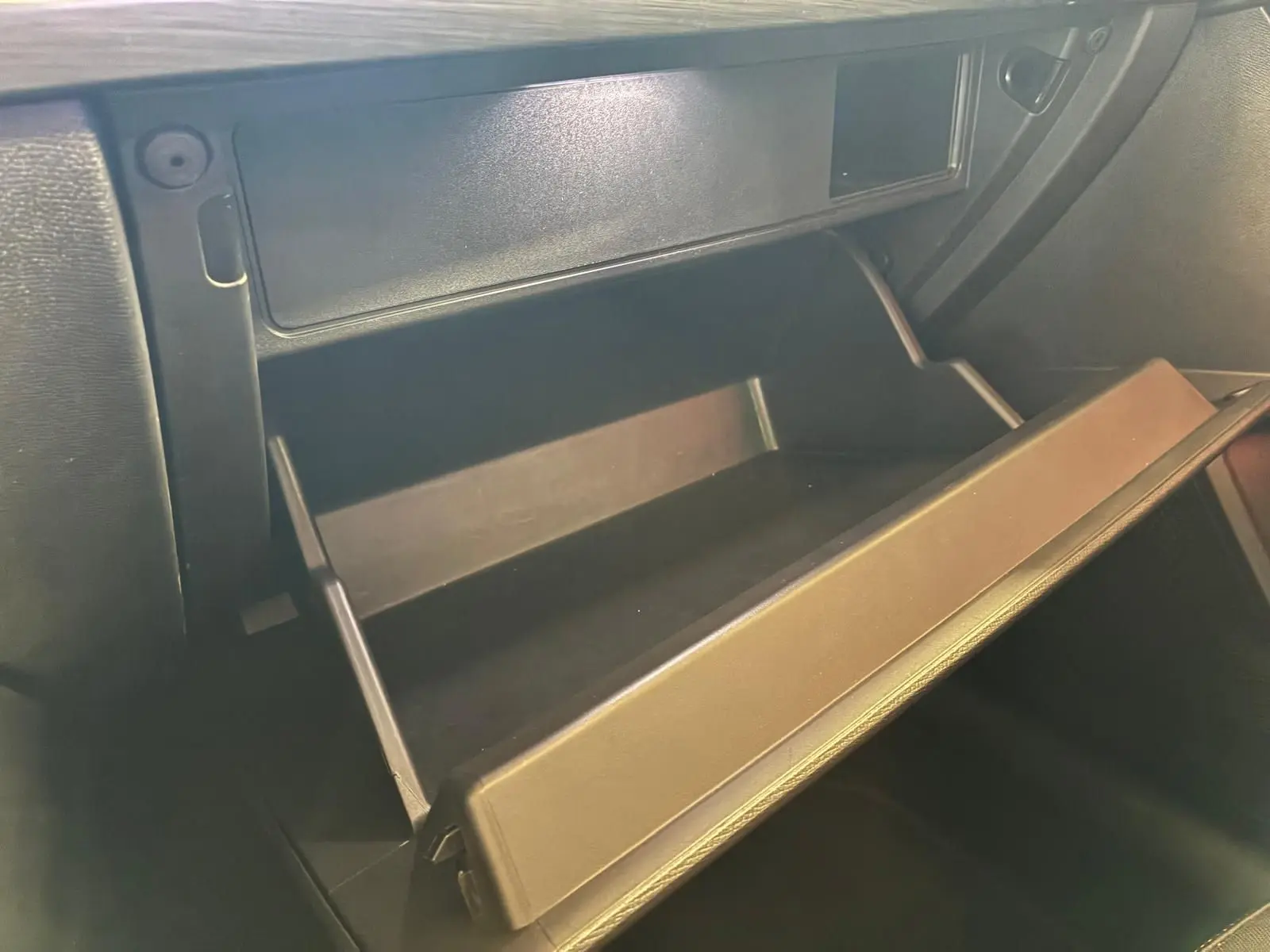 Gros plan sur la boîte à gants ouverte de la CUPRA LEON ST 2.0 TDI 150 DSG7, intérieur noir visible.