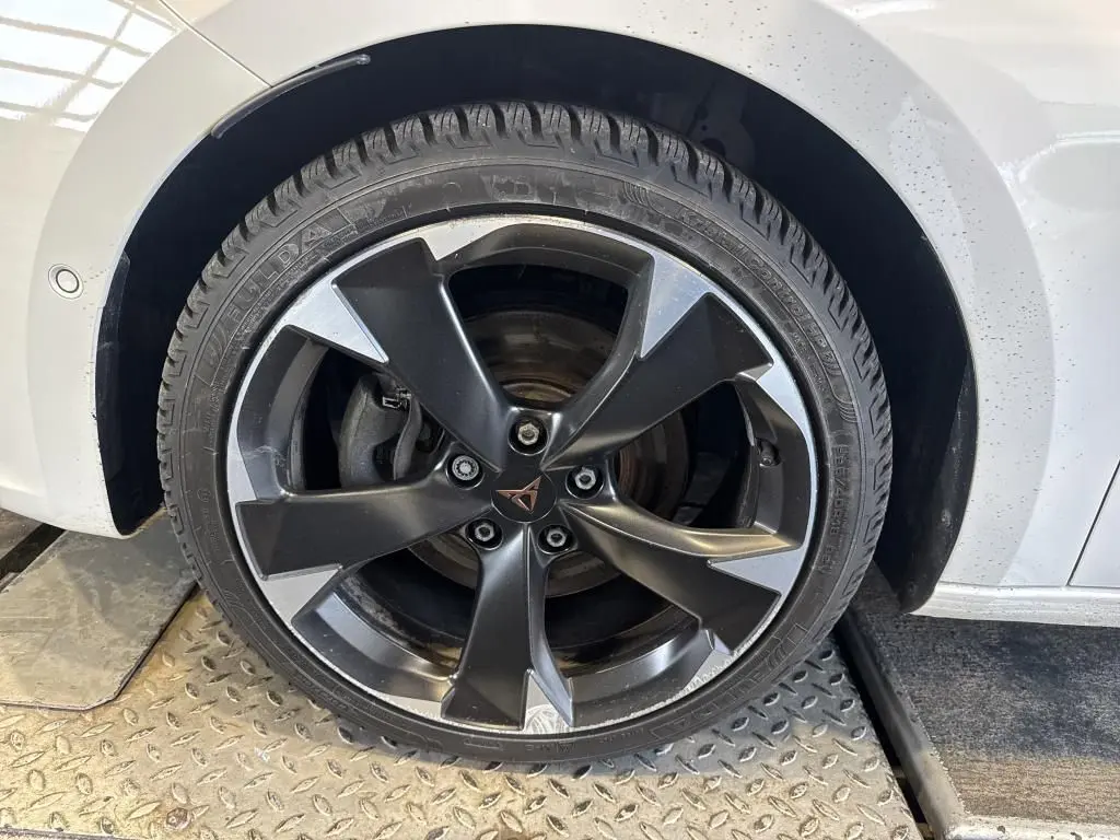 Gros plan sur la roue avant droite d'une CUPRA LEON ST blanche, avec jante alliage noire et argentée au design sportif.