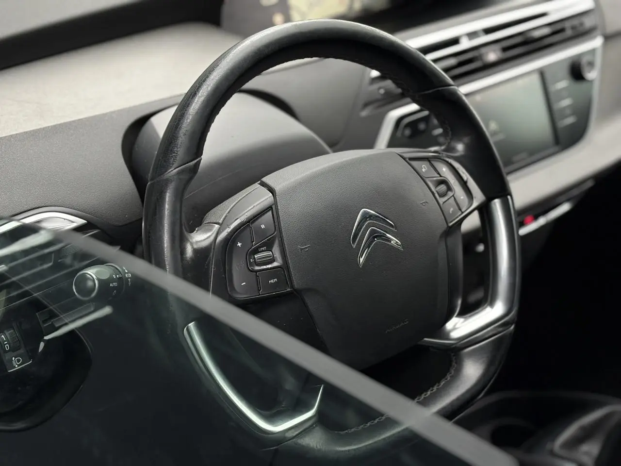 Gros plan sur le volant en cuir noir du Citroën C4 Spacetourer 2018, avec commandes intégrées et tableau de bord flou.