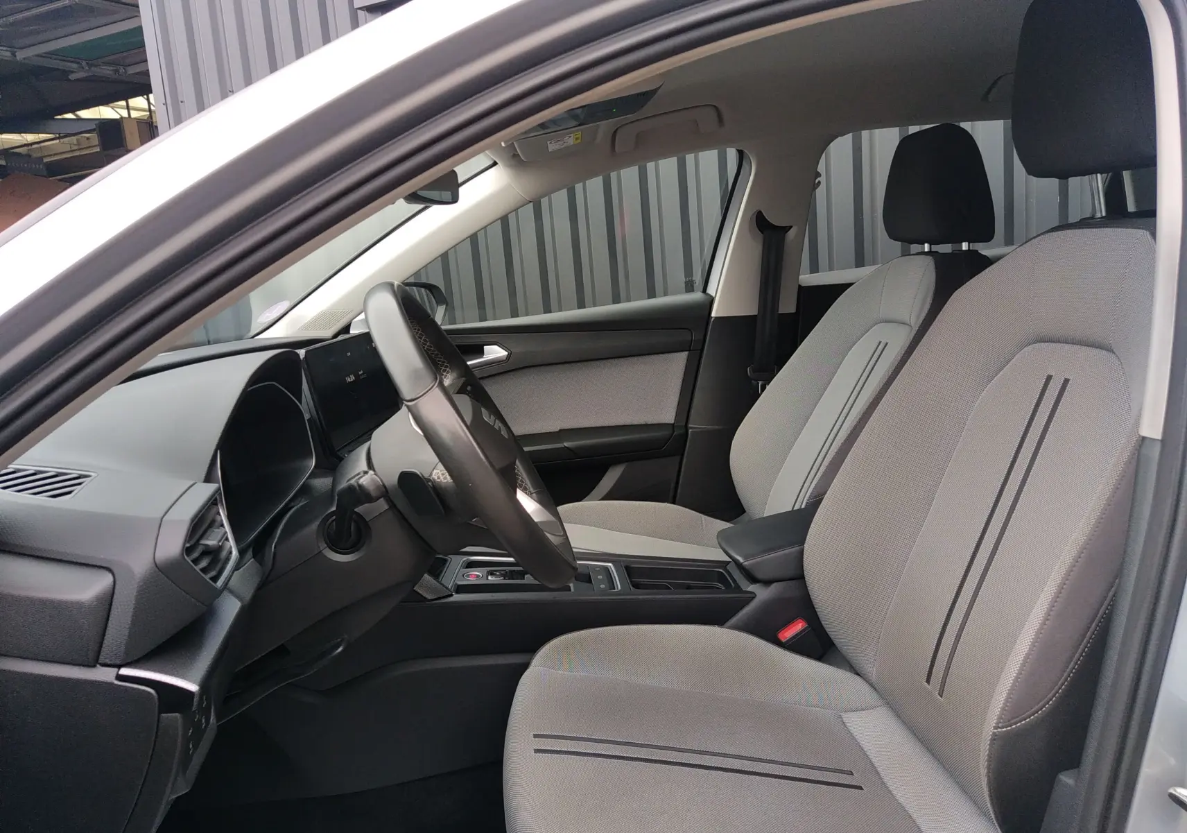 Intérieur clair de la SEAT LEON ST 2022, vue côté conducteur, sièges tissu gris avec bandes noires fines.