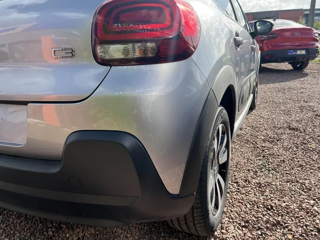 Vue 3/4 arrière droite d'une Citroën C3 gris nacré avec feux arrière distinctifs et protections noires sur le pare-chocs.