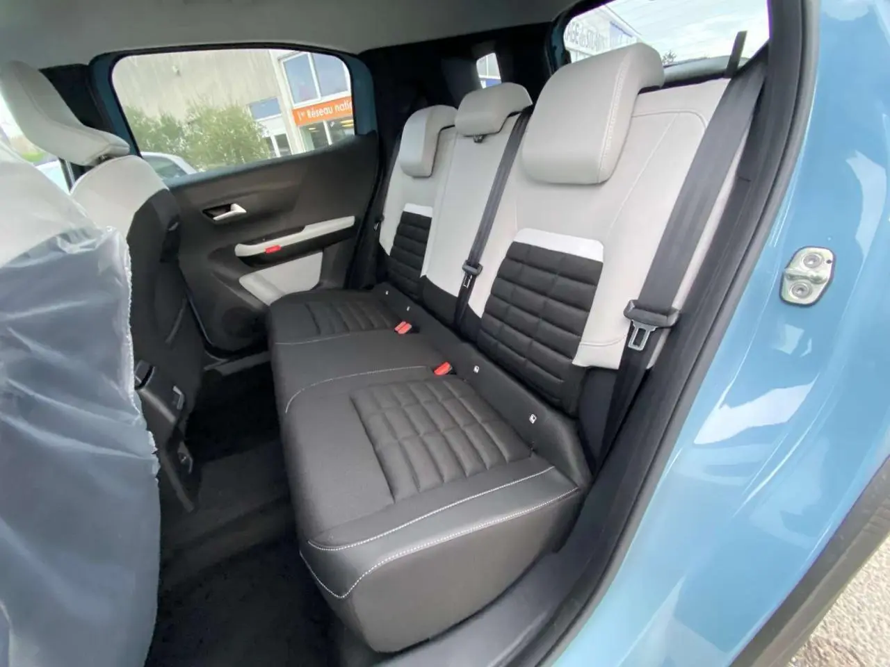 Vue intérieure côté arrière droit du Citroën C3 Aircross 2025 bleu Monte Carlo, montrant la banquette bicolore noire et grise.