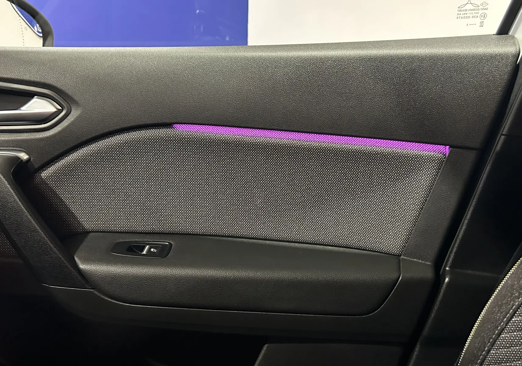 Détail de la porte côté droit du Renault Symbioz blanc nacré 2025 avec éclairage d'ambiance violet et bouton de fenêtre.