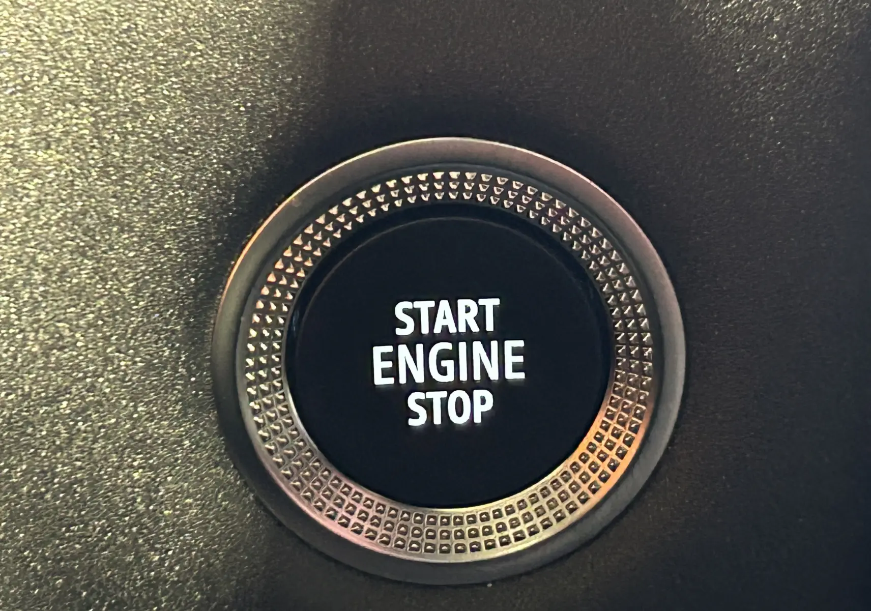 Bouton rond Start Engine Stop en gros plan sur tableau de bord noir du Renault Symbioz blanc nacré 2025 hybride.