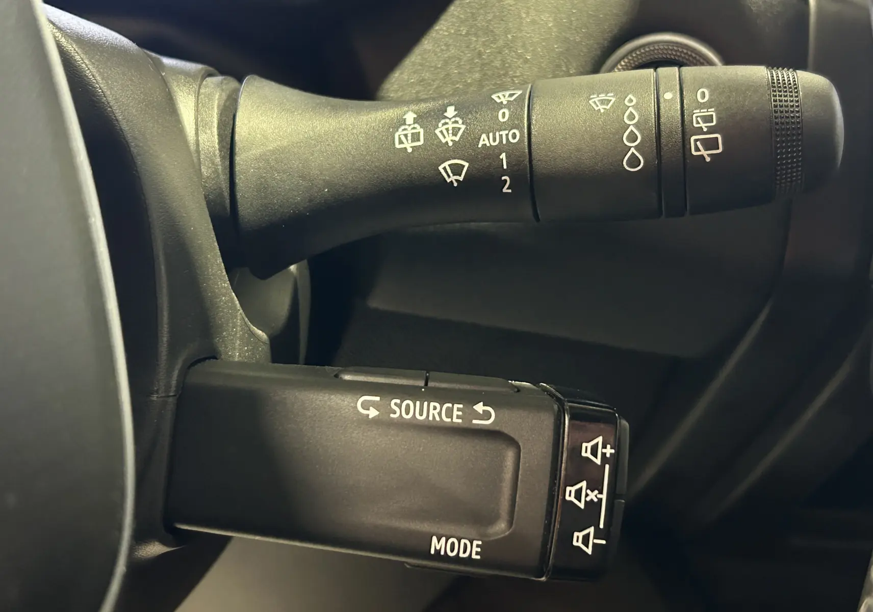 Gros plan sur les commandes de volant du Renault Symbioz 2025, avec boutons source et réglage essuie-glace visibles.