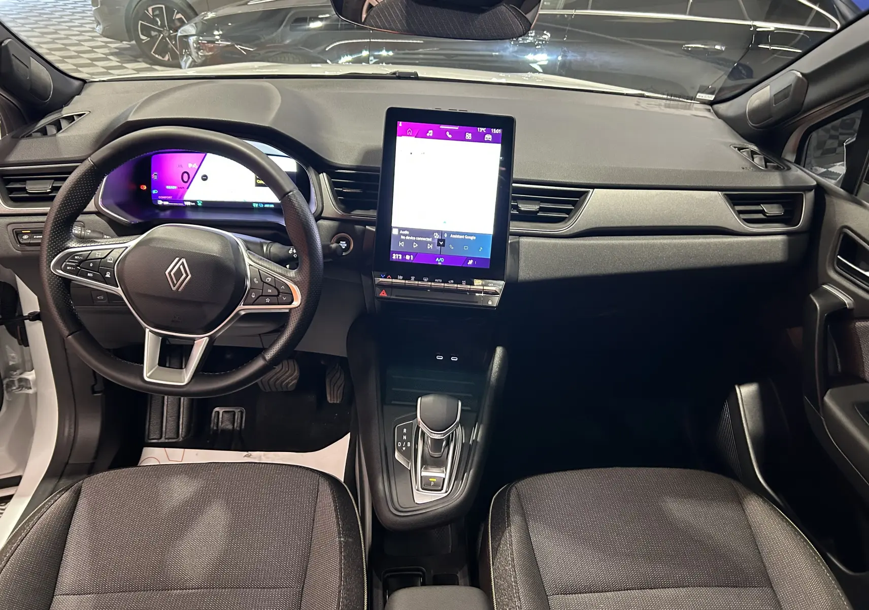 Vue intérieure avant du Renault Symbioz blanc nacré 2025, tableau de bord moderne avec écran tactile vertical et volant multifonction.