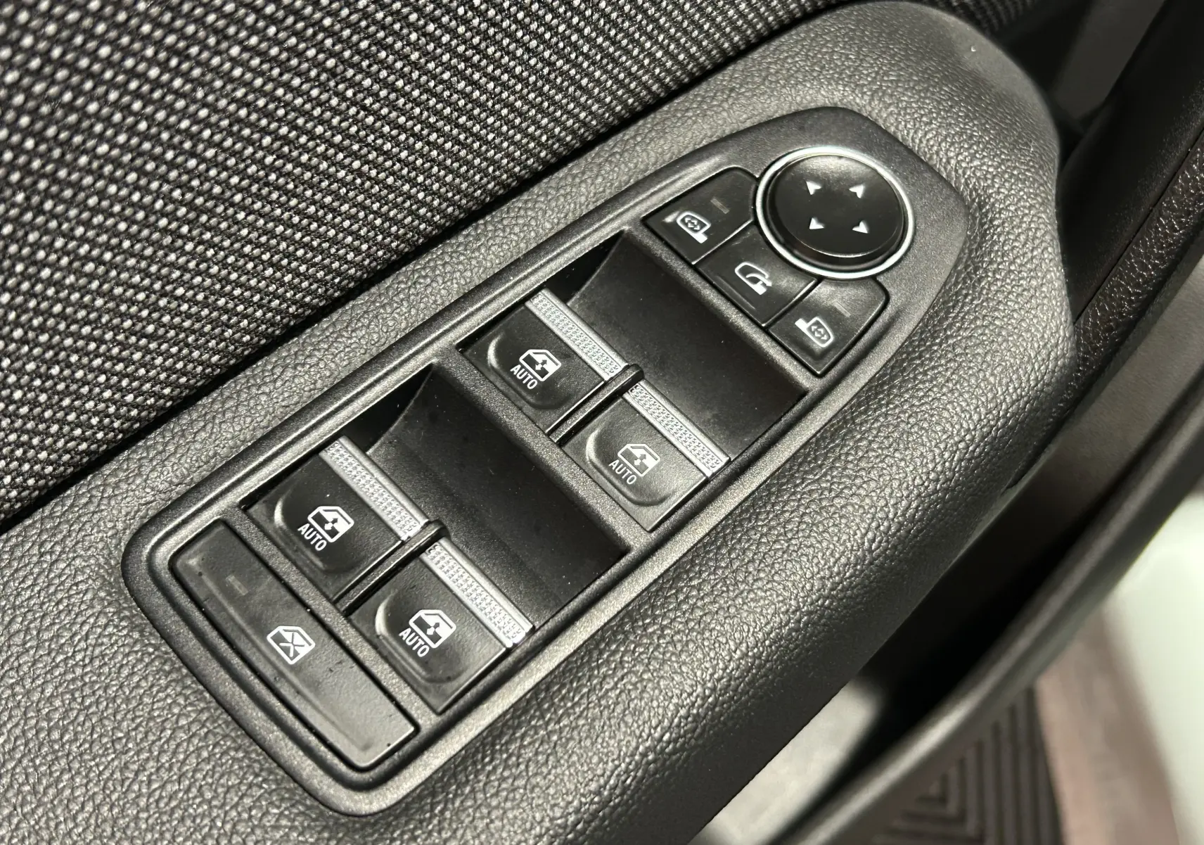 Panneau de commandes des vitres électriques et rétroviseurs sur la porte côté gauche d'une Renault Symbioz blanc nacré 2025.