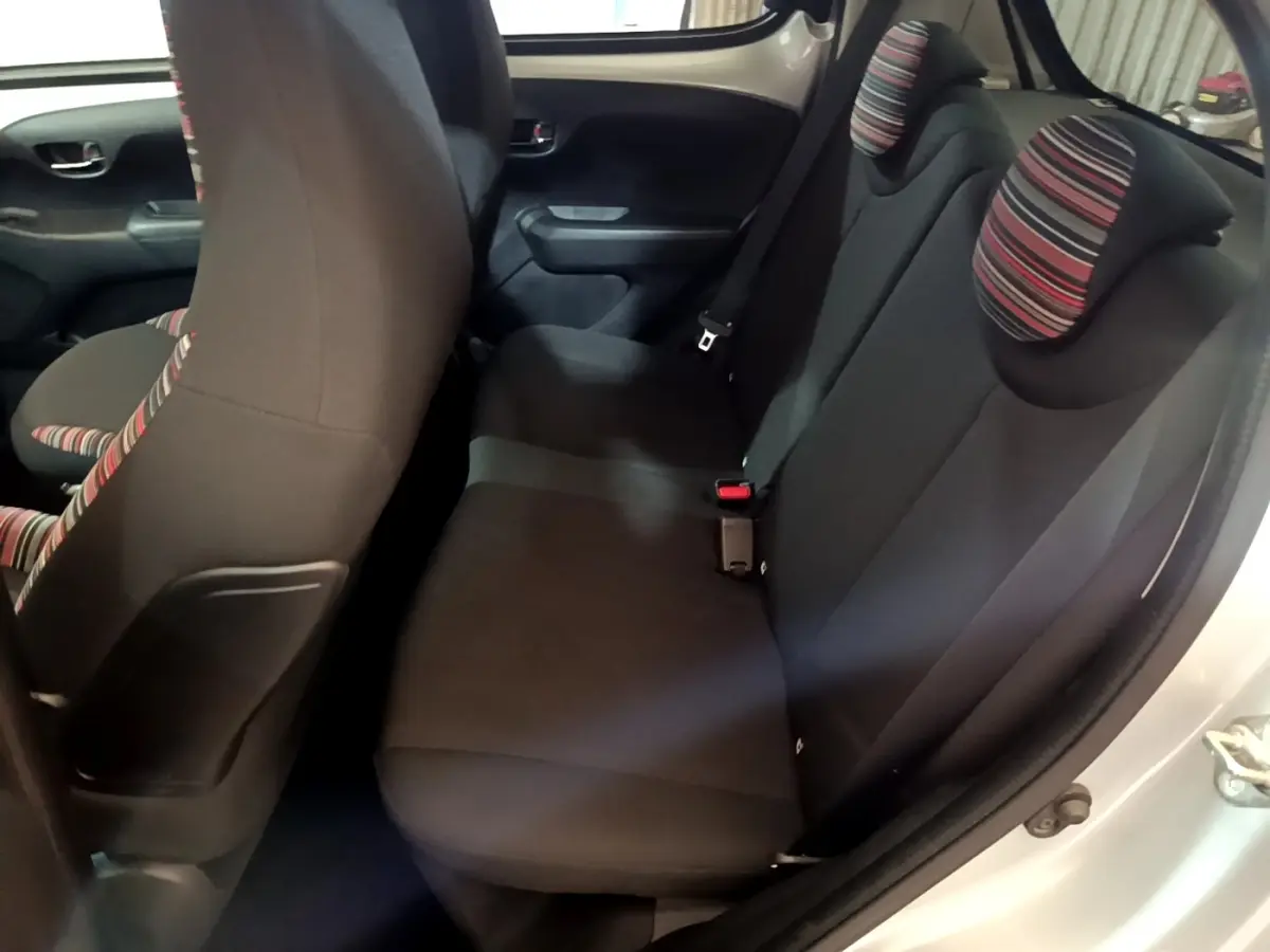 Vue intérieure côté droit sur la banquette arrière noire avec appuie-têtes rayés d'une Citroën C1 gris clair 2019.