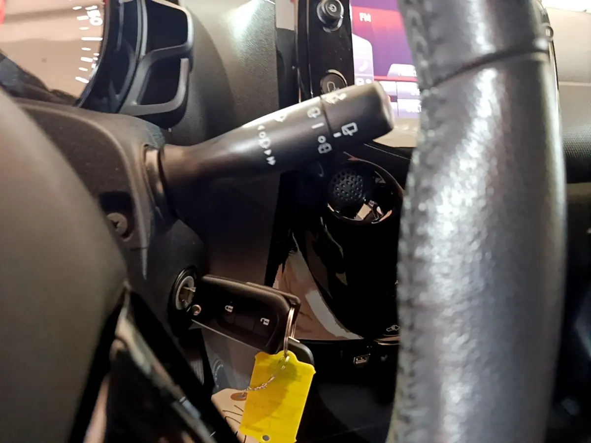 Gros plan intérieur côté gauche sur le volant cuir et la clé insérée dans le contact d'une Citroën C1 gris clair 2019.