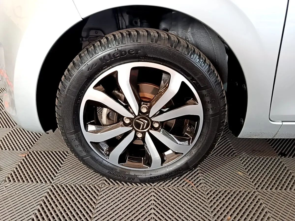 Gros plan sur la roue avant droite gris clair de la Citroën C1 avec jante alliage noire et argentée.