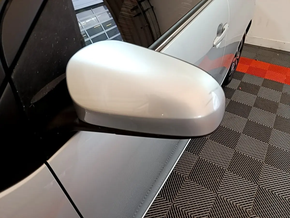 Gros plan sur le rétroviseur côté gauche d'une Citroën C1 gris clair, avec partie latérale visible en intérieur.