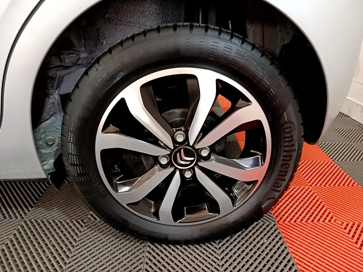 Gros plan sur la roue avant droite gris clair d'une Citroën C1 avec jante alliage noire et argentée.
