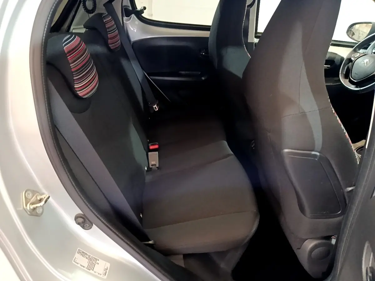 Vue intérieure côté gauche sur la banquette arrière noire avec appuie-têtes rayés d'une Citroën C1 gris clair 2019.