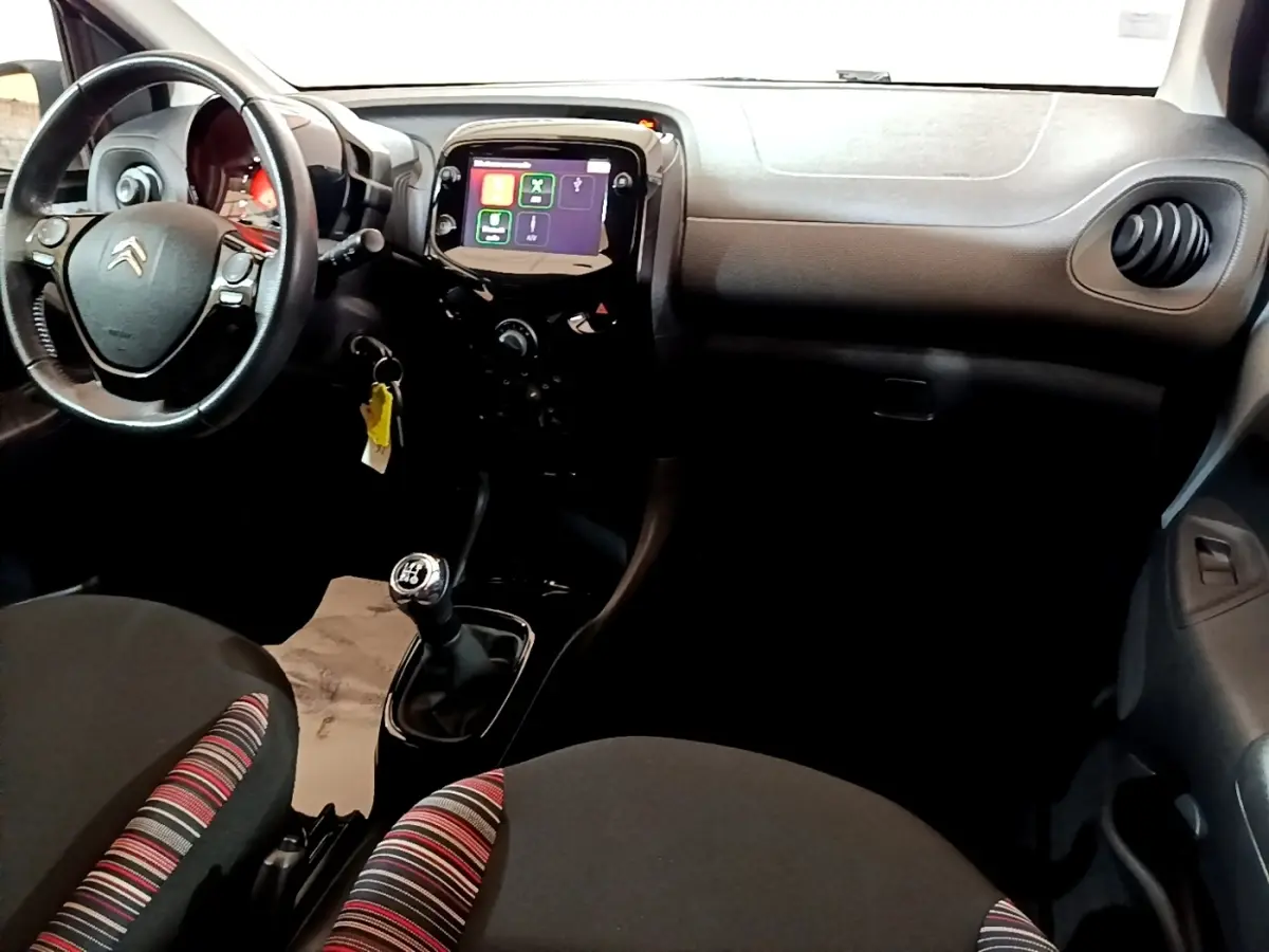 Intérieur de Citroën C1 2019 vu côté conducteur, tableau de bord noir avec écran tactile et volant cuir multifonctions.