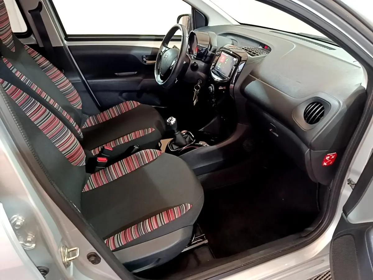Intérieur avant droit de Citroën C1 gris clair 2019, sièges à motifs rayés et tableau de bord avec écran tactile.