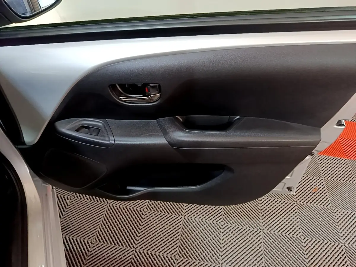 Vue rapprochée de la porte avant gauche gris clair de la Citroën C1 avec poignée intérieure noire et commande de vitre.