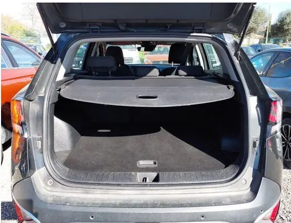 Vue arrière ouverte du coffre noir du KIA SPORTAGE 1.6 CRDI 136 BVM6 MOTION, montrant l'espace de chargement et la plage arrière.