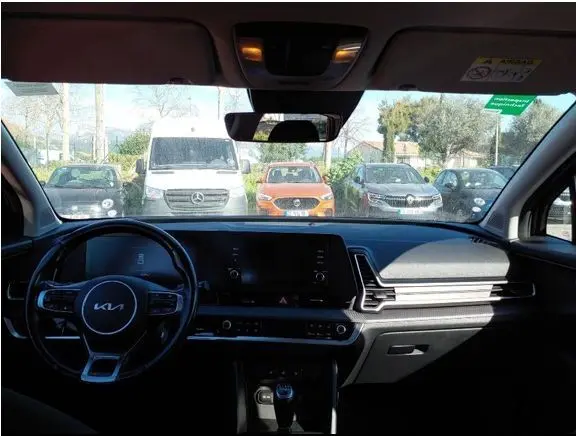 Vue intérieure du tableau de bord noir du Kia Sportage 2022, avec volant multifonction et écran central tactile.