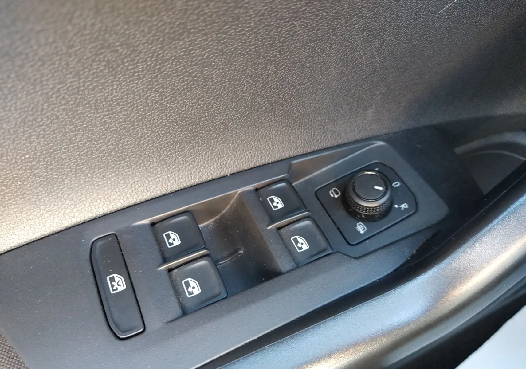 Gros plan sur les commandes des vitres et rétroviseurs côté gauche d'une Volkswagen Polo blanche 2021.