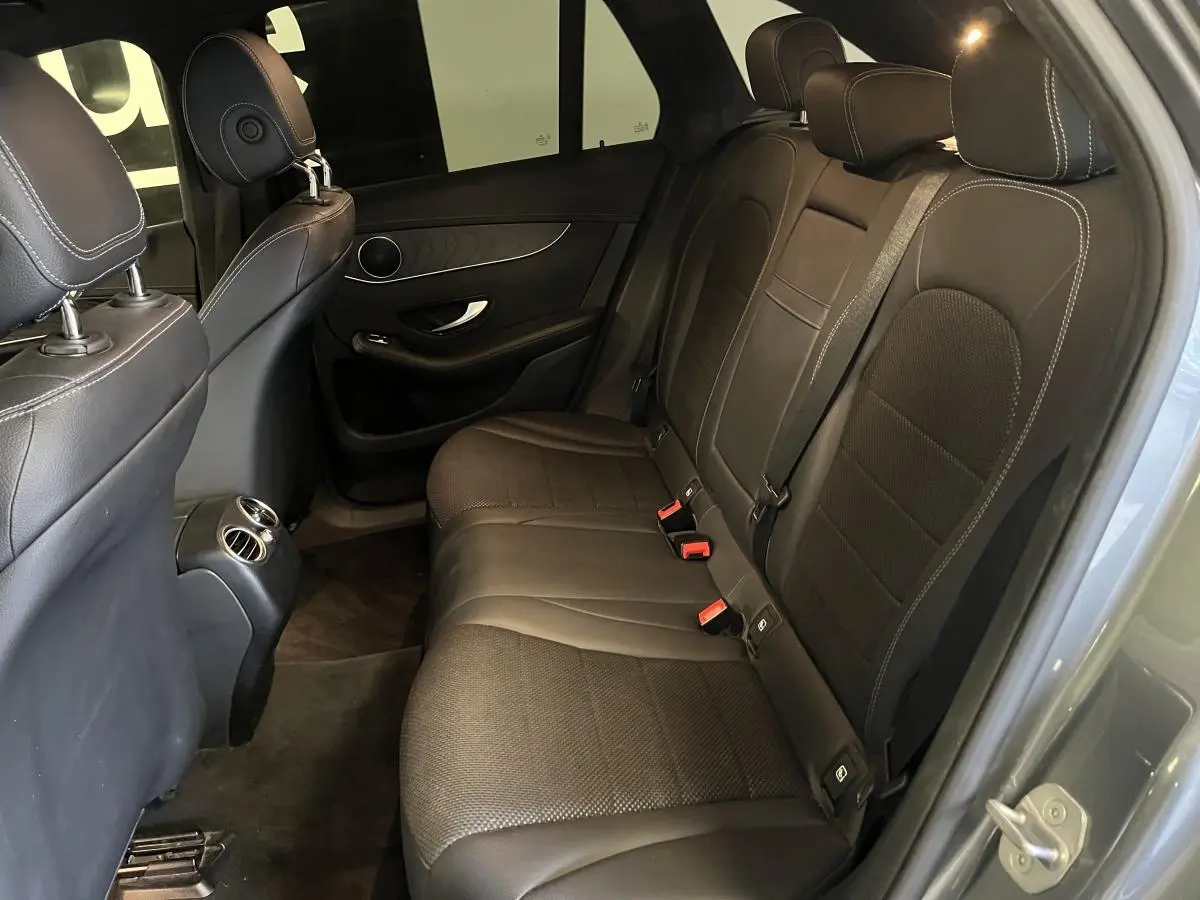 Vue intérieure côté droit montrant la banquette arrière en similicuir noir avec surpiqûres blanches du Mercedes GLC gris.