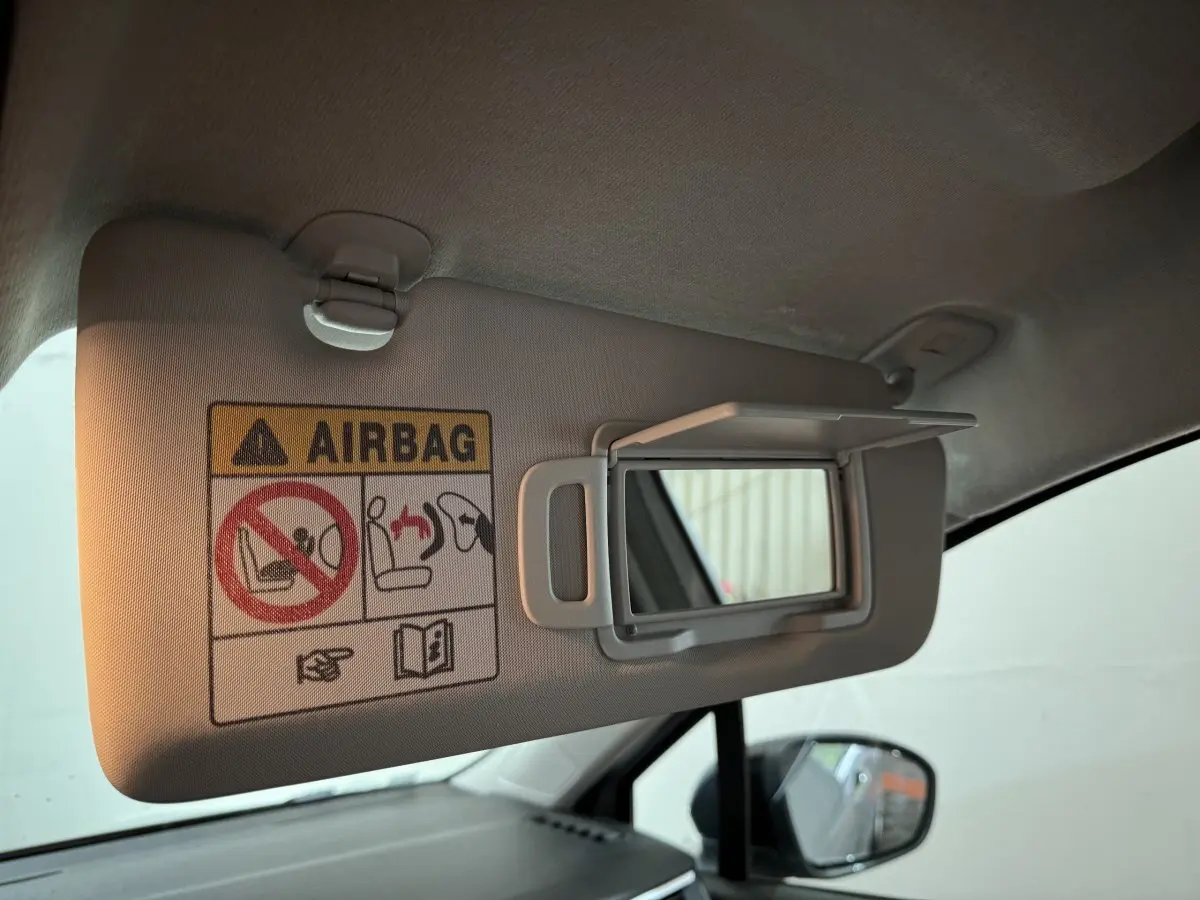 Détail du pare-soleil côté conducteur avec miroir ouvert et avertissement airbag dans une Renault Clio gris clair.