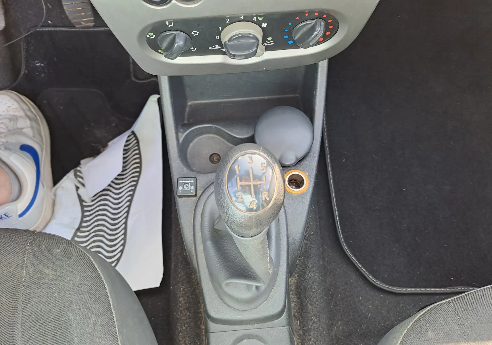 Le levier de vitesses manuel central d'une Dacia Sandero 2010 avec commandes de climatisation en haut.