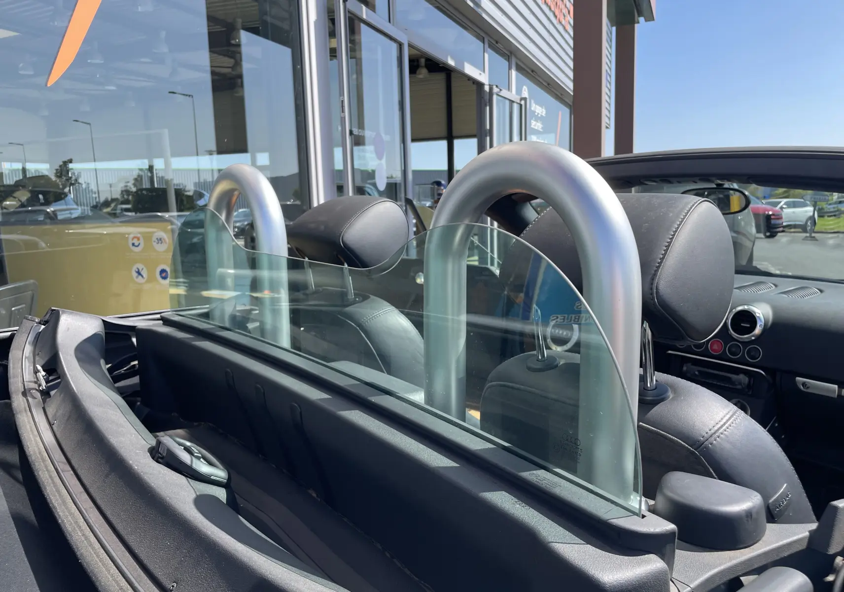 Vue intérieure arrière de l'Audi TT Roadster gris argent 2002, mettant en valeur les arceaux de sécurité et les sièges en cuir noir.