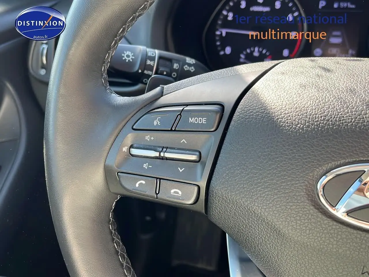 Gros plan sur le volant cuir de la Hyundai i30 gris argent 2024 avec commandes audio multifonctions intégrées