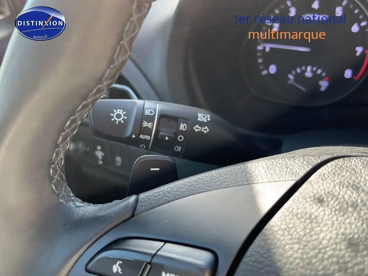 Gros plan sur le volant cuir et les commandes multifonctions d'une Hyundai i30 gris argent, tableau de bord en arrière-plan.