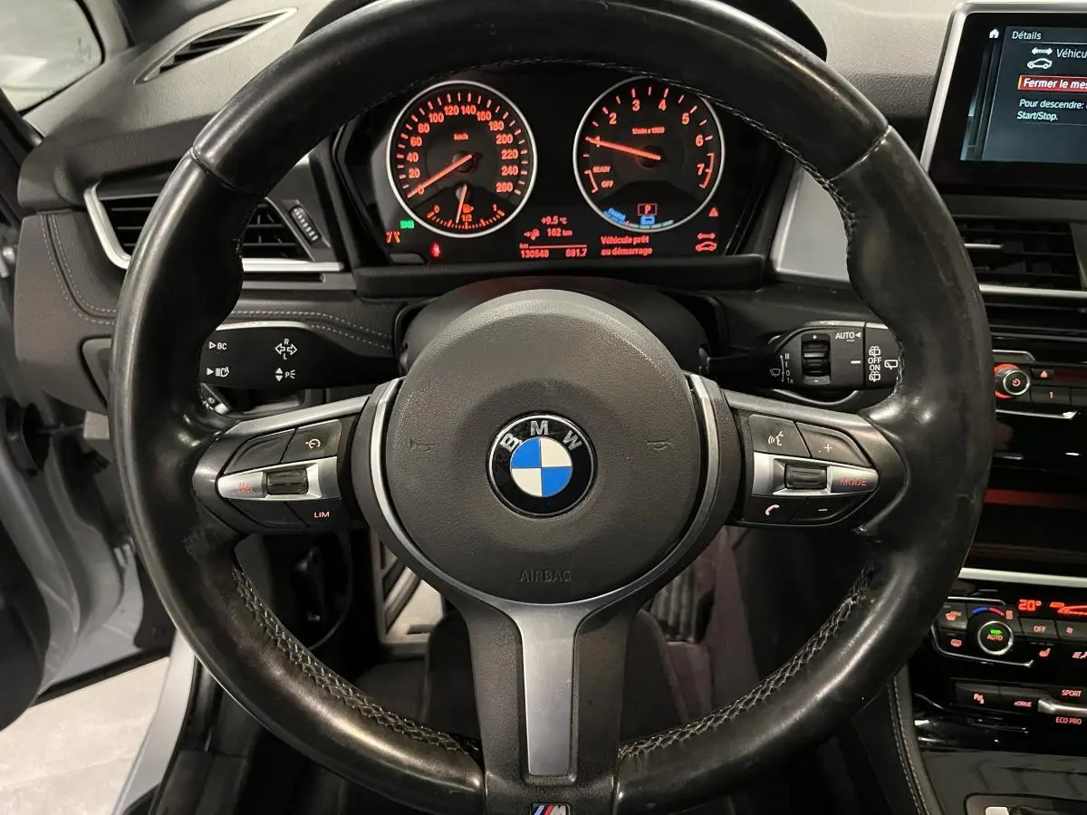 Vue intérieure centrée sur le volant cuir M de la BMW Série 2 225xe gris avec tableau de bord et écran multimédia visibles