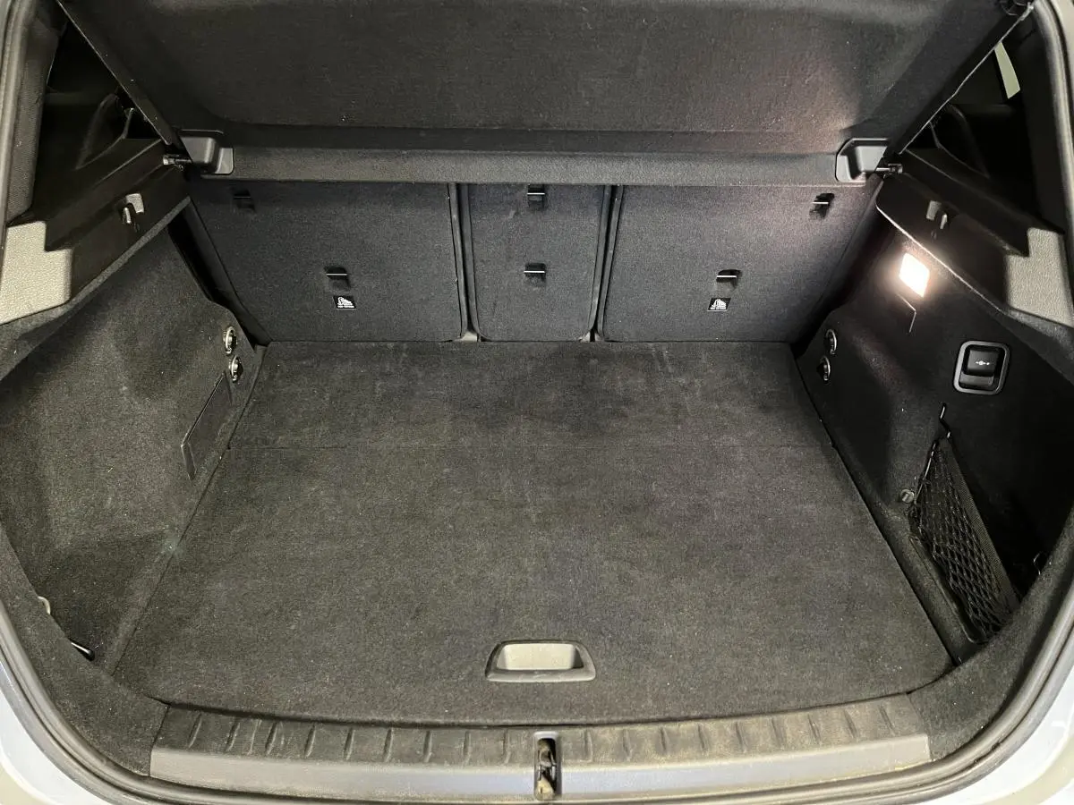Coffre ouvert de la BMW Série 2 225xe Active Tourer gris, montrant l'espace de chargement intérieur avec éclairage latéral.