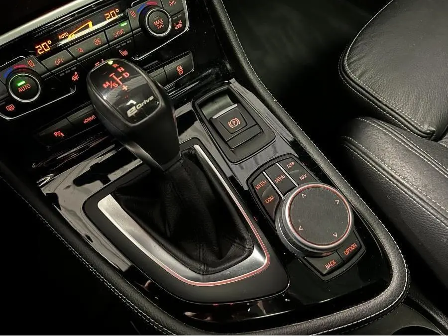 Gros plan sur la console centrale noire de la BMW Série 2 225xe Active Tourer avec levier de vitesses eDrive et commandes multimédia.