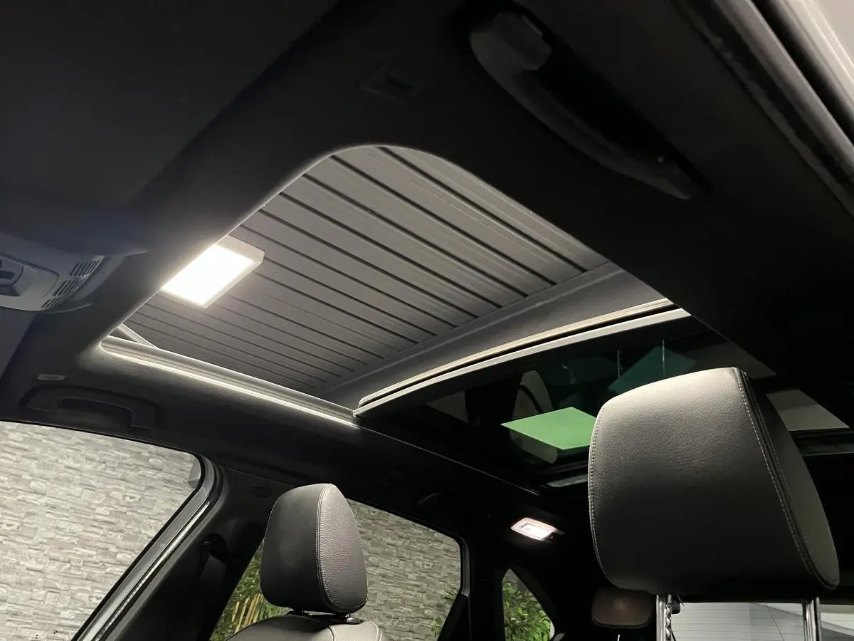 Vue intérieure du toit ouvrant panoramique en verre et des appuie-têtes en cuir noir d'une BMW Série 2 Active Tourer gris.
