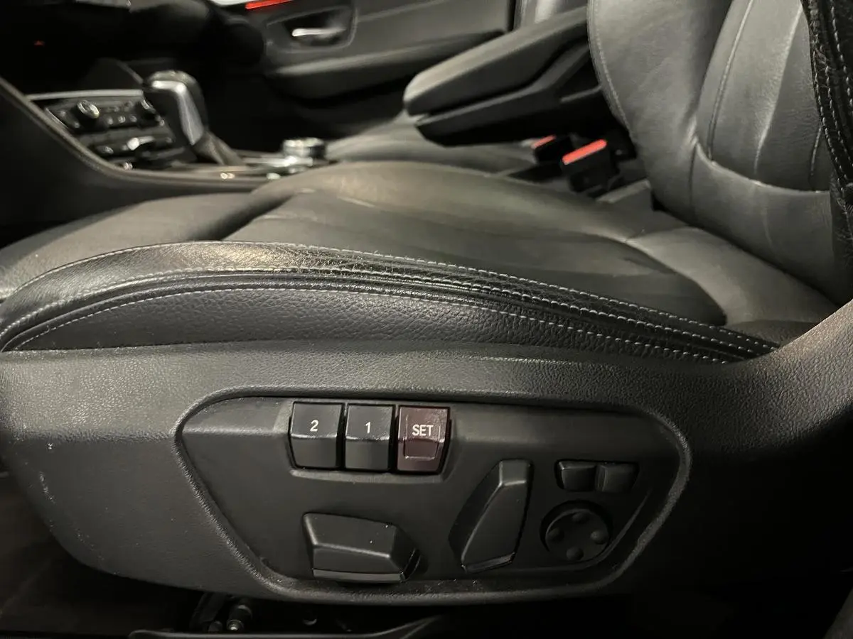 Détail des commandes électriques du siège conducteur en cuir noir dans une BMW Série 2 225xe Active Tourer gris.