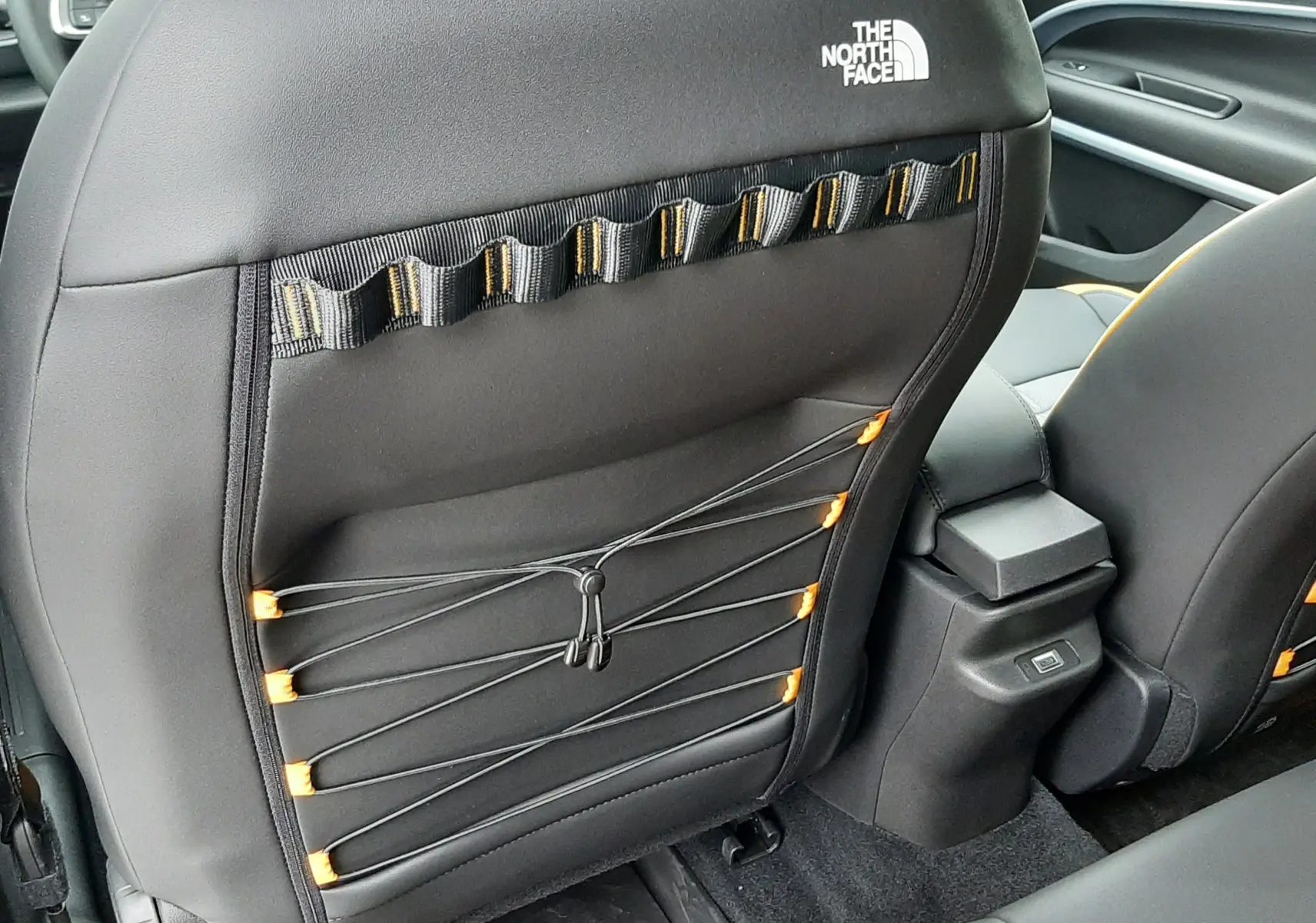 Vue arrière du siège avant droit noir avec logo The North Face et détails élastiques orange dans l’habitacle du Jeep Avenger 2025.