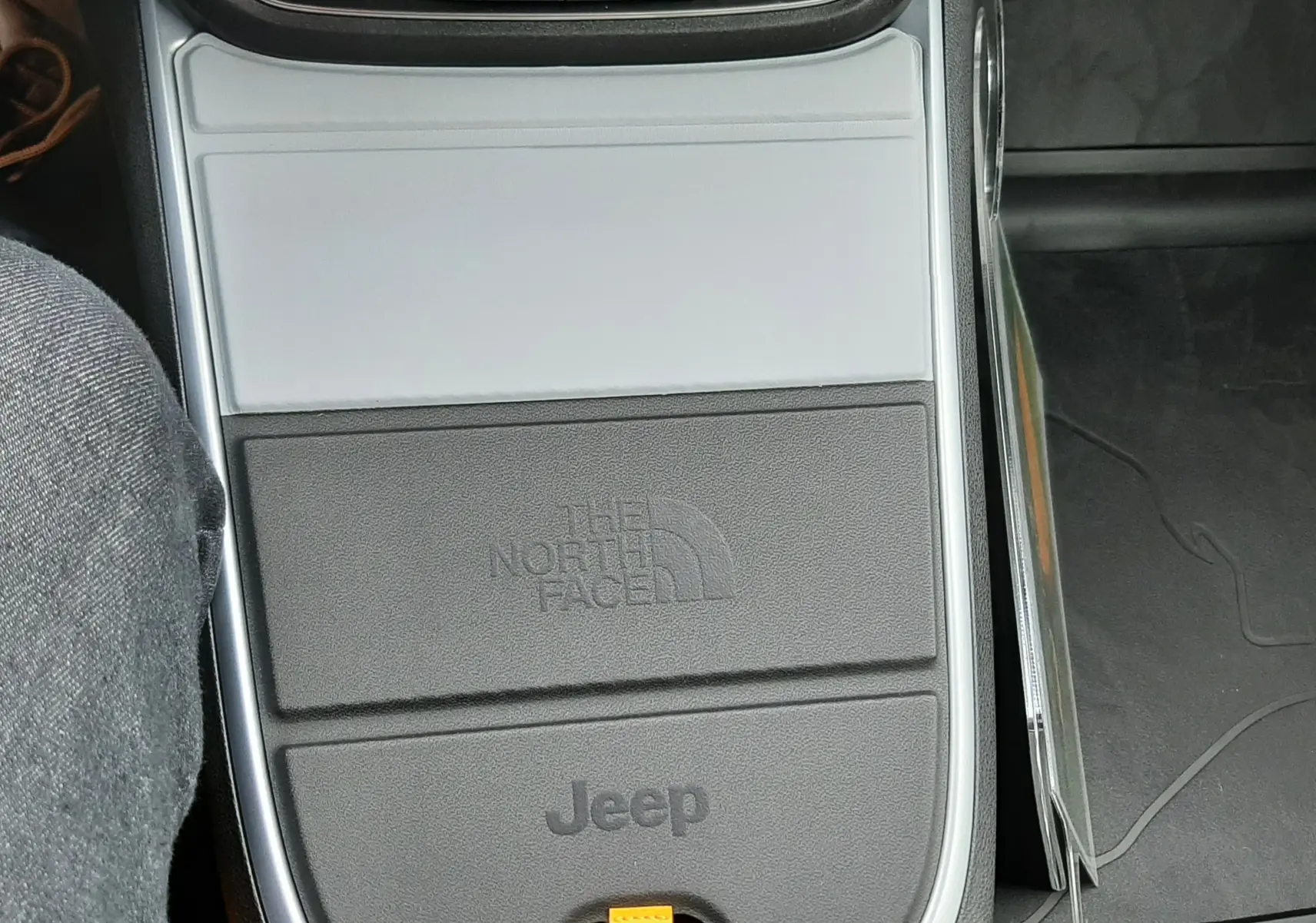 Vue rapprochée de la console centrale grise et noire du Jeep Avenger 2025 avec logo The North Face et commandes de boîte auto.