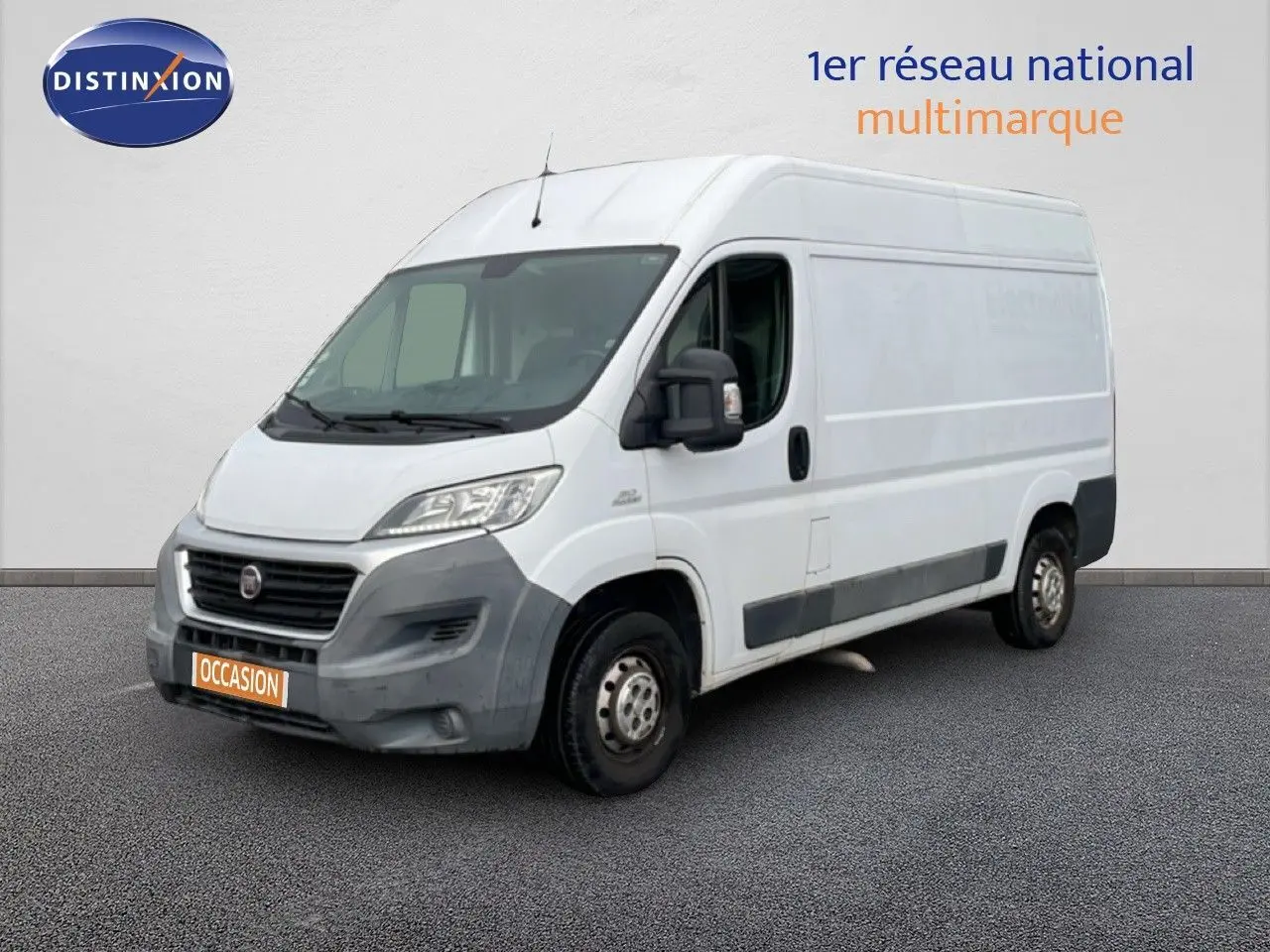 Vue 3/4 avant droit d’un fourgon FIAT Ducato blanc avec pare-chocs noirs et plaque orange "OCCASION".