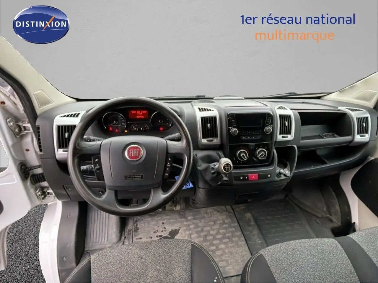 Vue intérieure du tableau de bord du Fiat Ducato Fourgon blanc de 2014, avec volant multifonction et levier de vitesses manuel.