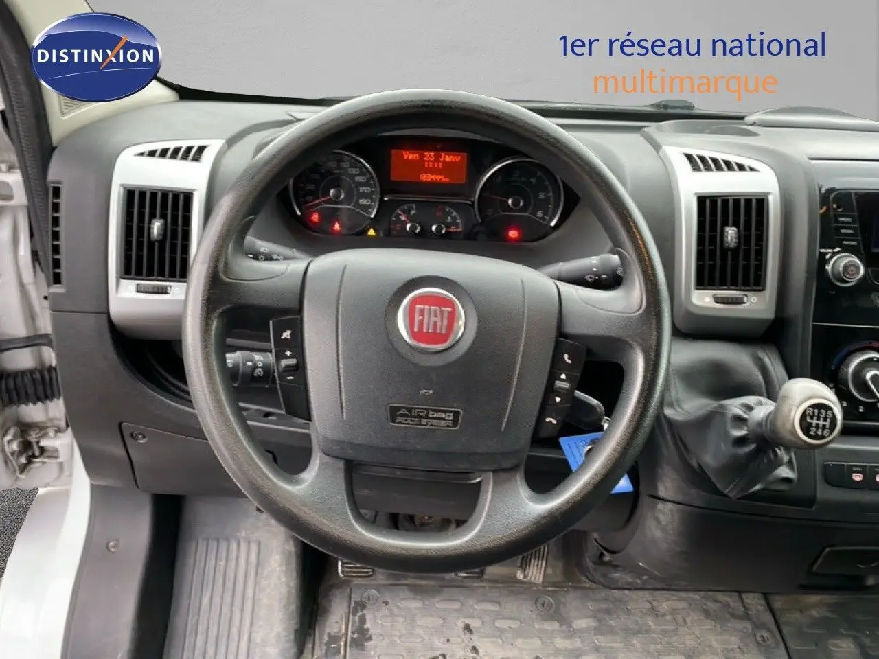 Vue intérieure centrée sur le volant FIAT et le tableau de bord du Ducato Fourgon blanc avec levier de vitesse manuel.