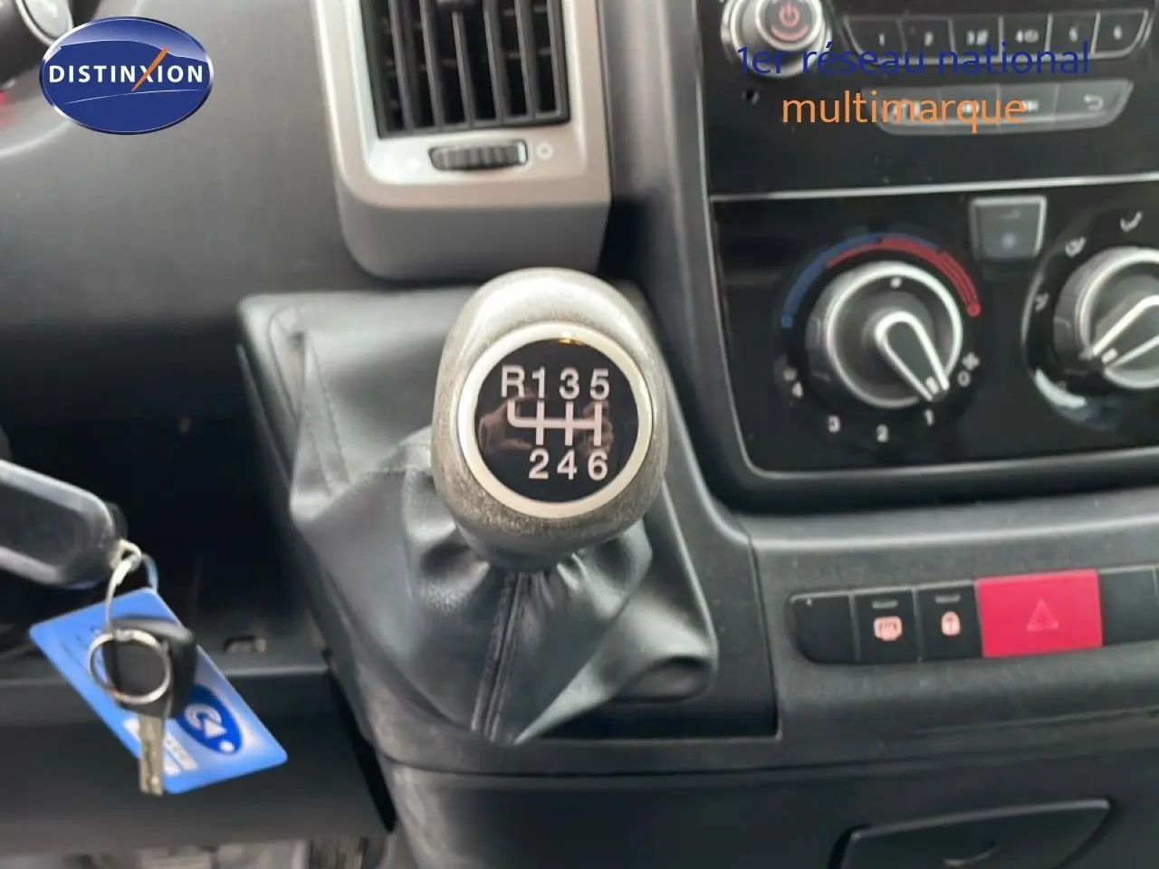 Gros plan sur le levier de vitesses manuel 6 rapports du Fiat Ducato Fourgon blanc, avec tableau de bord et commandes de climatisation visibles.