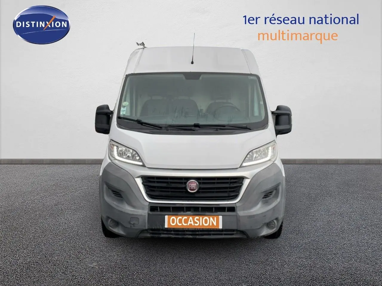 Vue frontale d’un fourgon Fiat Ducato blanc de 2014 avec calandre noire et plaque "OCCASION" orange.