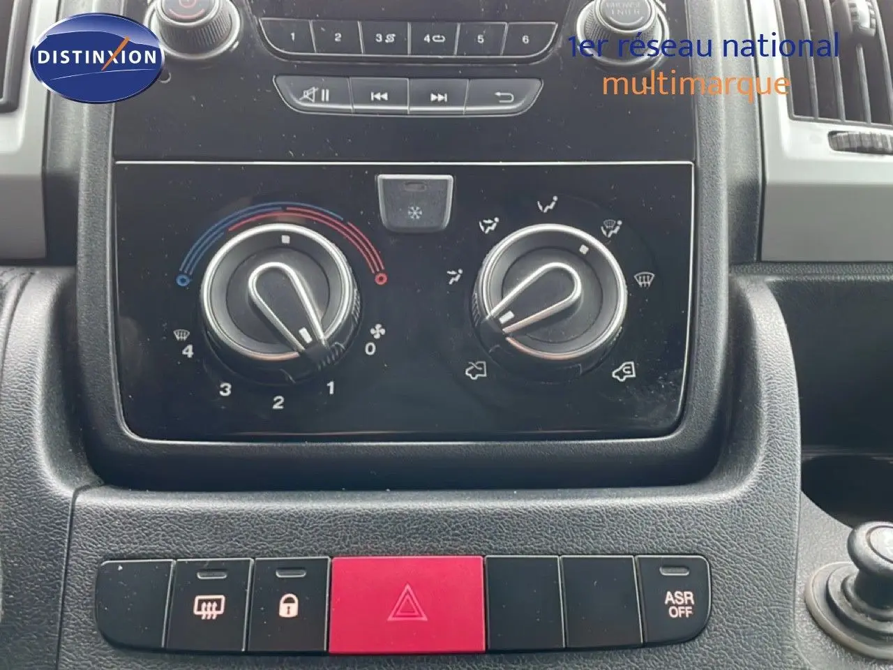 Gros plan sur la console centrale du Fiat Ducato Fourgon 2014, montrant les commandes de climatisation et les boutons de sécurité.