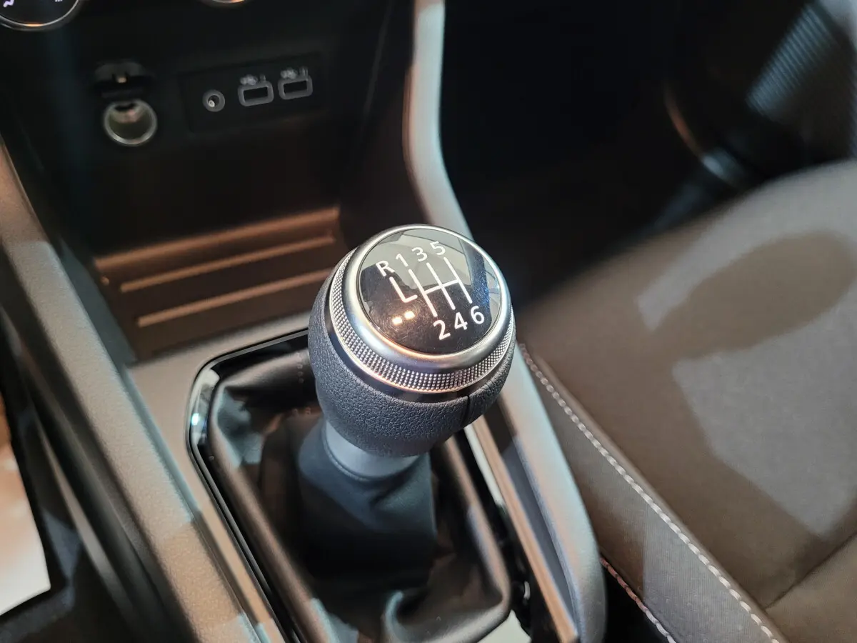 Gros plan sur le levier de vitesses manuel noir de la Renault Clio gris foncé, avec ports USB et prise 12V en arrière-plan.