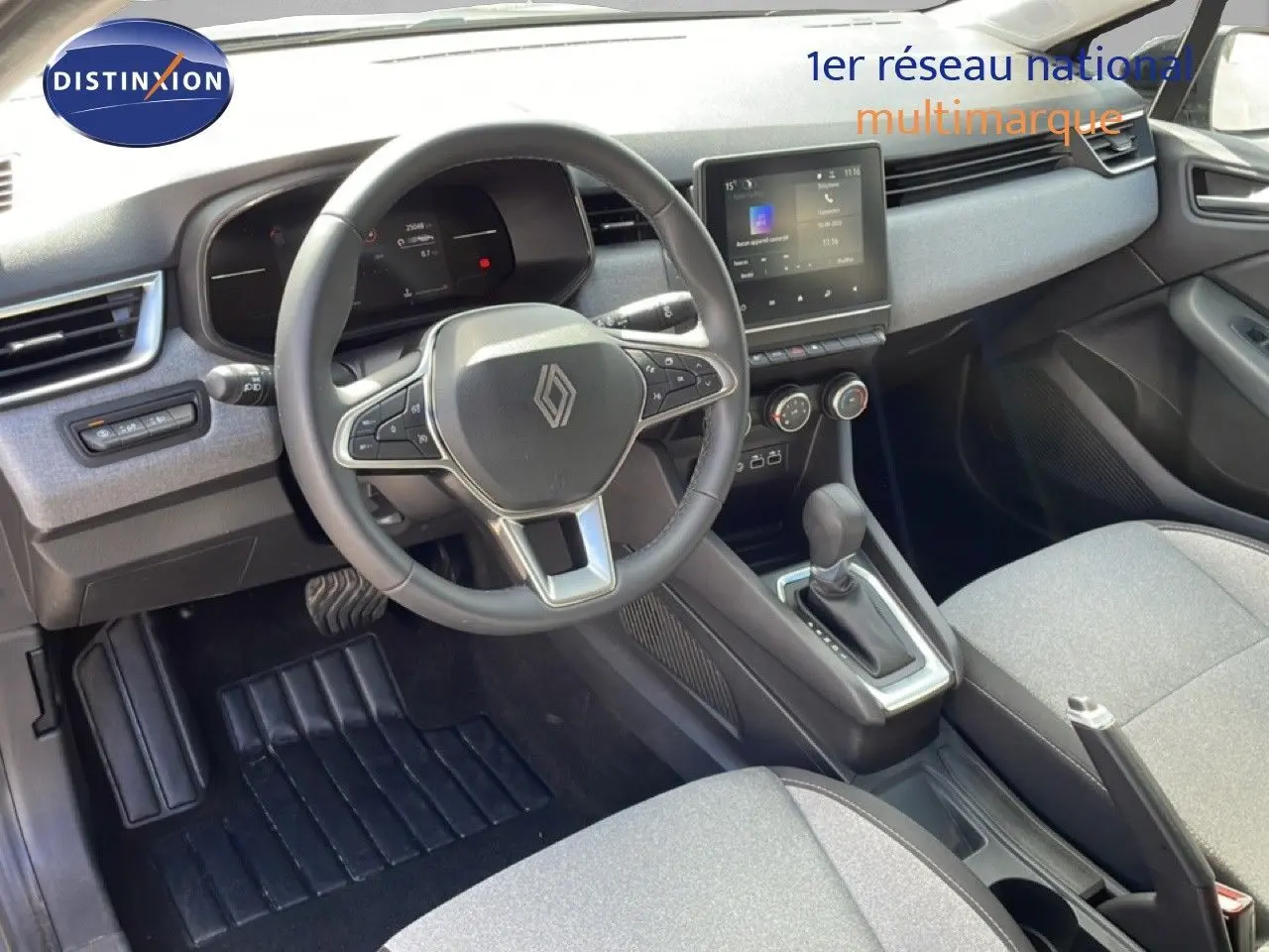 Vue intérieure de la Renault Clio 2025 gris schiste métal, volant cuir multifonction et console centrale avec boîte auto.